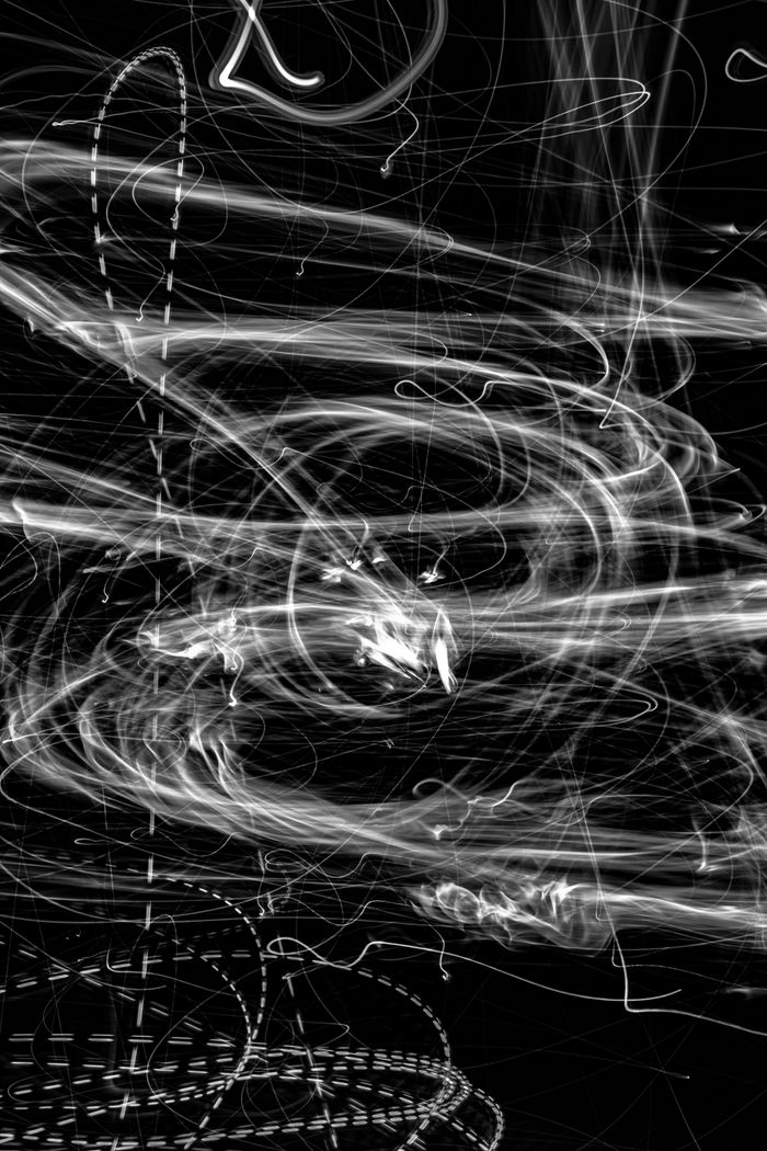 Enticing abstract photo of swirling light trails in monochrome, creating dynamic visual patterns.
